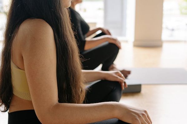 A person in a focused yoga pose on a mat in a bright studio.