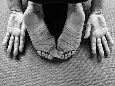 Close-up of hands and feet on a yoga mat, showing balance.